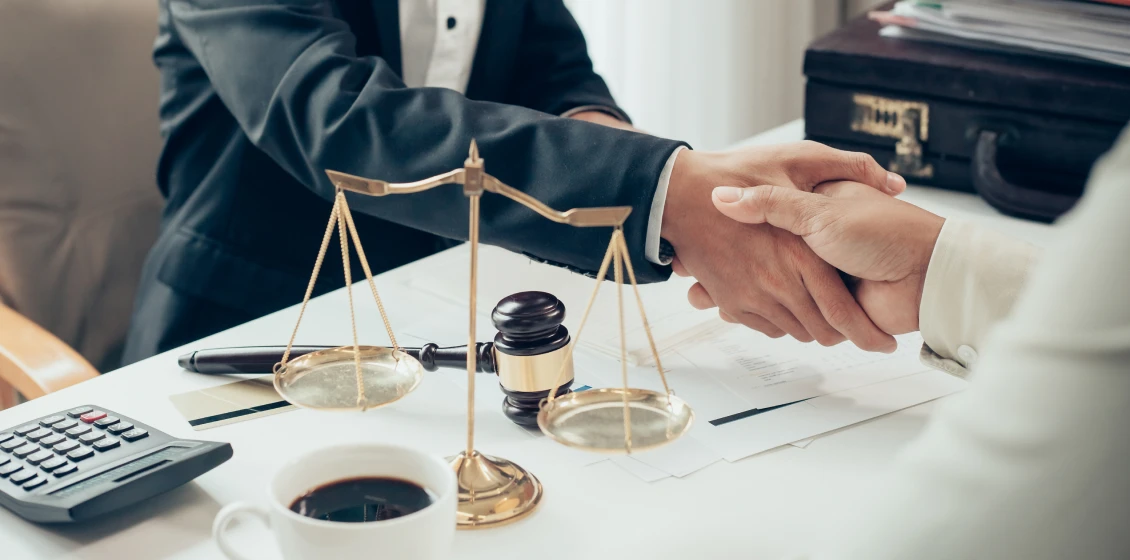 Handshake over legal documents and scales